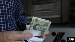 FILE - A man withdraws Iranian Rial notes from an automated teller machine in the capital Tehran on July 31, 2018. 