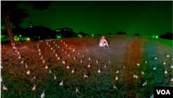 An activist sits among flags placed near the Washington Monument to memorialize the 180,000 people who have died in from the COVID-19 pandemic in the US in Washington. (August 27, 2020)