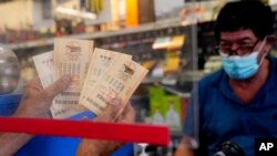 Maher Diab holds up his tickets at Bluebird Liquor, Oct. 28, 2022, in Hawthorne, Calif. Saturday's jackpot projected winnings of an estimated $825 million is the fifth-highest in U.S. history.