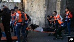 FILE - Palestinians evacuate a wounded man during clashes with Israeli security forces, outside Al Aqsa Mosque compound in Jerusalem's Old City, Apr. 15, 2022.