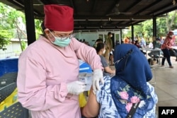 Seorang perawat (kiri) menyuntikkan vaksin booster Pfizer untuk COVID-19 di Jakarta, 29 Maret 2022. (ADEK BERRY/AFP)