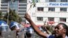 Un policier anti-émeute regarde un manifestant tenant des fleurs dans ses mains pour symboliser la paix à Harare, Zimbabwe, le 17 août 2016.