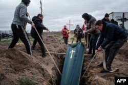 Relatives of Mykhailo Romaniuk, 58, who was shot dead on his bicycle on March 6, help to bury his coffin at a cemetery in Bucha, on April 19, 2022, during the Russian invasion of Ukraine.