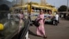A pedestrian passes a colorful car rapide, with her image reflected in the windshield of a modern Chinese brand King Long bus. Authorities plan to phase out cars rapide by late 2018. (R. Shryock/VOA)