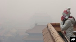 A woman adjusts her mask during a heavily polluted day in Beijing Tuesday, Dec. 22, 2015.