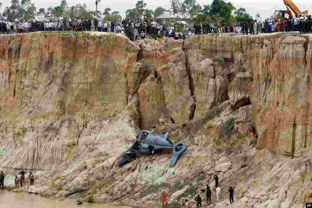 Militer Kamboja menggunakan crane untuk mengangkat helikopter yang jatuh di pinggiran ibukota Phnom Penh.