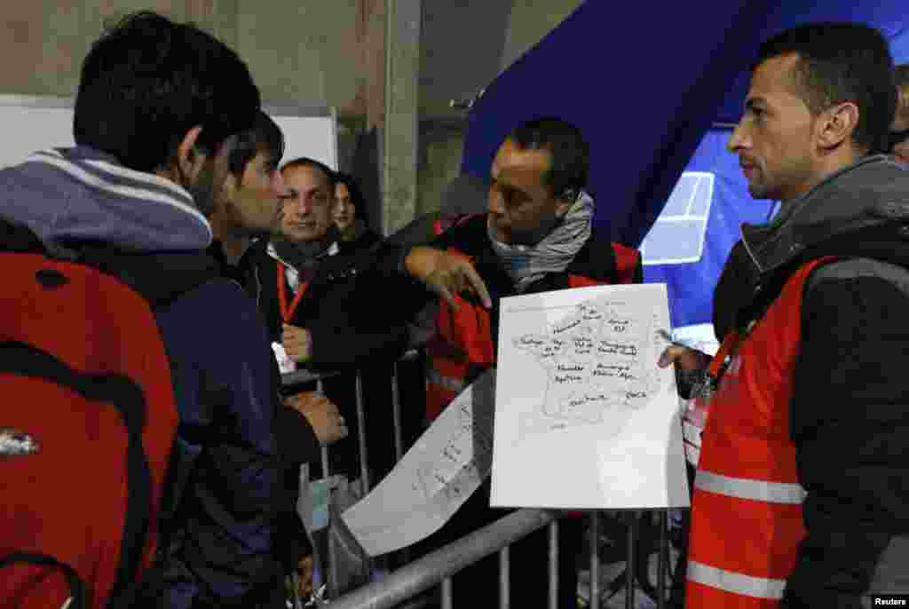 Para migran melihat peta Perancis di pusat pemrosesan pada hari kedua evakuasi dari kamp di Calais, Perancis (25/10). (Reuters/Philippe Wojazer)
