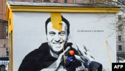 Un ouvrier peint sur un graffiti d'Alexei Navalny, critique du Kremlin, à Saint-Pétersbourg, le 28 avril 2021. L'inscription se lit comme suit : "Le héros des temps nouveaux".