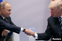 FILE - U.S. President Donald Trump shakes hands with Russian President Vladimir Putin during the their bilateral meeting at the G-20 summit in Hamburg, Germany, July 7, 2017. Trump has been criticized by former top U.S. intelligence officials for telling Putin it was a “great honor” to meet him.