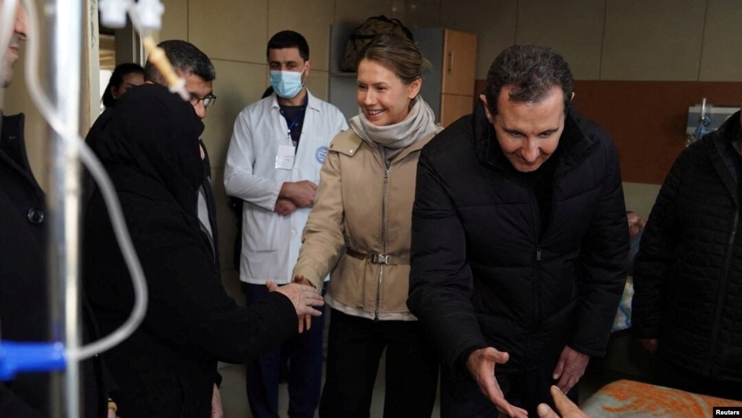 Prezidan Siryen an Bashar al-Assad ak madanm ni Asma vizite yon granmoun ki siviv tranblemannte a nan lopital inivesite Aleppo a, nan foto sa a ke Prezidans la distribye bay lapres 10 Fevriye 2023.