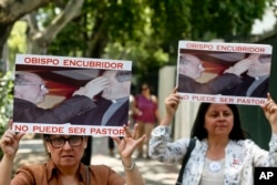 Members of the movement Laicos de Osorno hold images of the Rev. Fernando Karadima, and his protege Juan Barros, bishop of Osorno, with a message that reads in Spanish: "A bishop who covers up cannot be a priest," during a demonstration in front of the Apostolic Nunciature, in Santiago, Chile, Jan. 12, 2018.