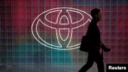 Seorang pria berjalan melewati logo Toyota di Tokyo Motor Show, di Tokyo, Jepang 24 Oktober 2019. (Foto: REUTERS/Edgar Su)