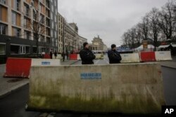 Armed police officers stand behind concrete blocks for protection near the Brandenburg Gate in Berlin, Friday, Dec. 23, 2016.