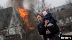 A man and a child escape from the town of Irpin, after heavy shelling on the only escape route used by locals, while Russian troops advance towards the capital of Kyiv, in Irpin, near Kyiv, Ukraine, March 6, 2022.