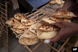 Seorang pekerja di sebuah toko roti, di el-Sharabia, distrik Shubra, Kairo, Mesir, mengumpulkan roti 'tradisional Mesir baladi', Rabu, 2 Maret 2022. Konflik Rusia-Ukraina berpotensi menciptakan kerawanan pangan dan membuat lebih banyak orang jatuh miskin di tempat-tempat seperti Mesir dan Lebanon, di mana makanan didominasi oleh roti yang disubsidi pemerintah. (Foto AP/Nariman El-Mofty)