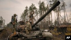 A Ukrainian serviceman takes a selfie standing on a destroyed Russian tank after Ukrainian forces overran a Russian position outside Kyiv, Ukraine, March 31, 2022. 