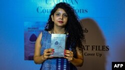 FILE - Indian journalist and author, Rana Ayyub poses with her self published book 'Gujarat Files' during the launch event in New Delhi, May 27, 2016.