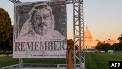 FILE - Penulis Turki Hatice Cengiz, kanan, tunangan jurnalis Saudi Jamal Khashoggi, berpose di samping potret Khashoggi setelah dipamerkan di National Mall, Washington, 1 Oktober 2021.