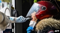 FILE - A health worker takes a swab sample from a woman to test for the COVID-19 coronavirus in the Jing'an district in Shanghai, China, on Dec. 23, 2022. 