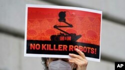 A woman holds up a sign while taking part in a demonstration about the use of robots by the San Francisco Police Department outside of City Hall in San Francisco, Monday, Dec. 5, 2022. (AP Photo/Jeff Chiu)