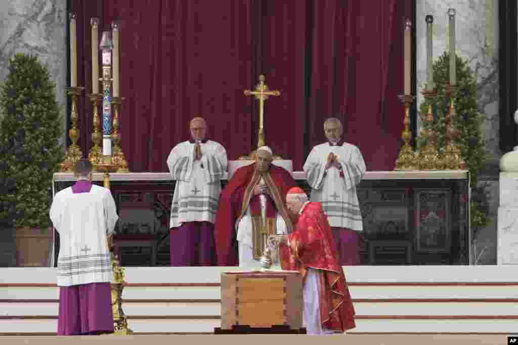 Pope Francis, center, watches as Cardinal Giovanni Battista Re, center right, blesses the coffin of late Pope Benedict XVI in St. Peter's Square at the Vatican, Jan. 5, 2023.