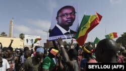 ARCHIVES - Des manifestants brandissent des drapeaux et un portrait du maire de Ziguinchor Ousmane Sonko lors d'un rassemblement à la place de l'Obélisque à Dakar, le 8 juin 2022.