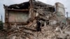 Seorang pria mencari dokumen teman mereka yang terluka di puing-puing sebuah rumah apartemen yang hancur setelah penembakan Rusia di daerah perumahan di Chuhuiv, wilayah Kharkiv, Ukraina, Sabtu, 16 Juli 2022. (Foto: AP)