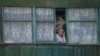 A local resident stands in the window as she looks at a school building damaged by a Russian military strike, amid Russia's invasion on Ukraine, in the town of Kostiantynivka, Ukraine, July 13, 2022. 