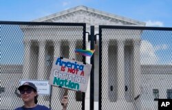 A demonstrator holds a sign in front of the U.S Supreme Court Monday, July 18, 2022, in Washington. (AP Photo/Mariam Zuhaib)