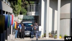 FILE - In this file photo taken on Feb. 14, 2018 a police van and uniformed and plainclothes police officers are seen inside the compound of the controversial business family Gupta in Johannesburg. 