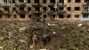 Ukrainian military personnel inspect the site of a missile strike in front of a damaged residential building in Dobropillia, in the Donetsk region, Ukraine, April 30, 2022.