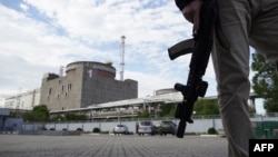FILE - A security person stands in front of the Zaporizhzhia nuclear power plant, amid the ongoing Russian military action in Ukraine, Sept. 11, 2022. 
