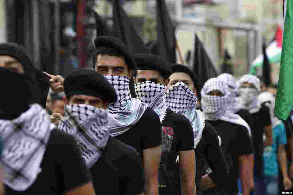 Palestinians wearing traditional headscarves and carrying black flags attend a demonstration calling for an end to the Israeli offensive in the Gaza Strip after Eid al-Fitr prayers, at Al-Baqaa Palestinian refugee camp, near Amman, Jordan, July 28, 2014.
