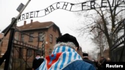 FILE - Survivors and guests walk past the "Arbeit Macht Frei" gate at the former Nazi German concentration and extermination camp Auschwitz, during the ceremonies marking the 73rd anniversary of the liberation of the camp and International Holocaust Victims Remembrance Day, in Oswiecim, Poland, Jan. 27, 2018. 