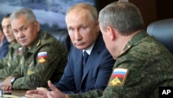 FILE - Russian President Vladimir Putin, center, and Russian Defense Minister Sergei Shoigu, left, observe the main stage of the Kavkaz-2020 strategic command-and-staff exercises at the Kapustin Yar training ground, Russia, Sept. 25, 2020.