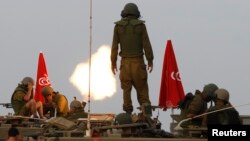 FILE - Israeli soldiers stand on an armored personnel carrier (APC) outside the central Gaza Strip as they fire mortar shell towards Gaza before a ceasefire was due, early Aug. 1, 2014. 