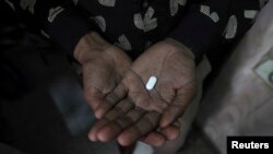 FILE - An AIDS patient is seen holding an antiretroviral drug.