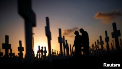 FILE - A couple grieves in a cemetery Coral Gables, Fla. Suicide rates rose in nearly every U.S. state from 1999 to 2016, the U.S. Centers for Disease Control and Prevention reported on June 7, 2018.