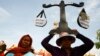 A protester from Boeung Kak lake holds a cutout of a scale symbolizing justice as she joins other villagers, who were allegedly evicted from their homes without adequate compensation, during a rally in front of the Justice Ministry in Phnom Penh, Cambodia, file photo. 