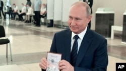 លោក​ប្រធានាធិបតី Vladimir Putin បង្ហាញ​លិខិត​ឆ្លង​ដែន​ទៅ​កាន់​សមាជិកគណកម្មាធិការ​បោះឆ្នោត​នៅ​ការិយាល័យ​បោះឆ្នោតមួយ​ក្នុង​ទីក្រុង​មូស្គូ​ប្រទេស​រុស្ស៊ី​កាលពី​ថ្ងៃទី​០១ ខែកក្កដា ឆ្នាំ២០២០។