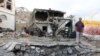 Men stand next to a crater made by a car bomb attack near the presidential palace in the southern port city of Aden, Yemen, Jan. 28, 2016. 