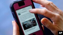 FILE - A mobile phone is used to access news from The Huffington Post on Facebook, in Los Angeles, April 28, 2015.