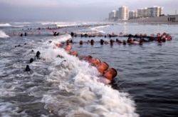 This May 4, 2020, photo provided by the U.S. Navy shows SEAL candidates participating in "surf immersion" during Basic Underwater Demolition/SEAL training at the Naval Special Warfare Center in Coronado, Calif.