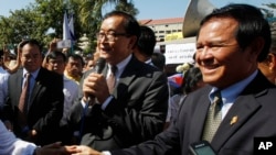 Opposition leader of Cambodia National Rescue Party Sam Rainsy, center, delivers a speech next to his Deputy President Kem Sokha, right, during a gathering to mark Human Rights Day, in front of National Assembly, in Phnom Penh, file photo. 