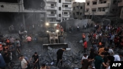 Tingatinga likiondoa kifusi huku watu wakikusanyika katika eneo la makazi huko Rafah upande wa kusini mwa Ukanda wa Gaza baada ya Israeli kufanya shambulizi Octoba 15, 2023.