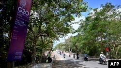 Motorcyclists ride past a banner for the G-20 Foreign Ministerial Meeting scheduled to be held this July 7-8, outside the meeting venue in Nusa Dua on Indonesia's resort island of Bali on July 5, 2022.