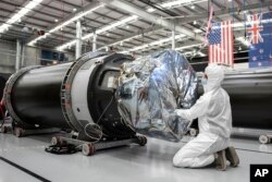 In this photo released by Rocket Lab, a technician works on a component of Rocket Lab's Electron rocket ahead of the launch on the Mahia peninsula in New Zealand on March 10, 2022. (Rocket Lab via AP)