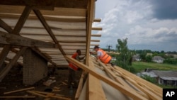 Civilians rebuild homes destroyed by Russian strikes, in Yahidne village, northern Chernihiv region, Ukraine, June 29, 2022. A few months after Russian troops retreated, people are repairing their homes, and a strong wind occasionally picks up the bitter smell of ashes.