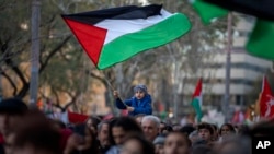 FILE - Seorang anak laki-laki mengibarkan bendera Palestina saat para demonstran berbaris dalam protes mendukung warga Palestina dan menyerukan gencatan senjata segera di Gaza, di Barcelona, Spanyol, 20 Januari 2024. (AP/Emilio Morenatti)