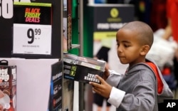 A boy looks over a Black Friday sale item at a J.C. Penney store, Nov. 24, 2017, in Seattle.